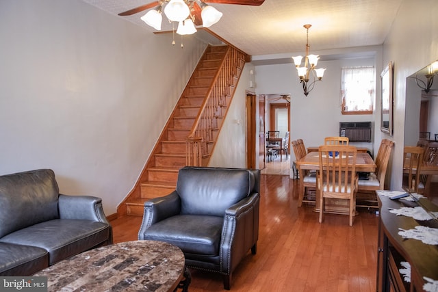 living room featuring ceiling fan with notable chandelier and hardwood / wood-style floors