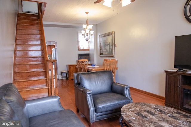 living room with hardwood / wood-style flooring and ceiling fan with notable chandelier