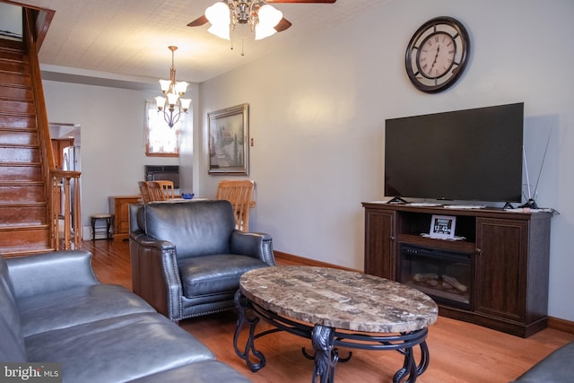 living room with ceiling fan with notable chandelier and wood-type flooring