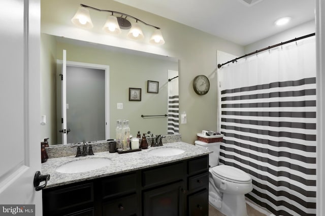 bathroom featuring toilet and dual bowl vanity