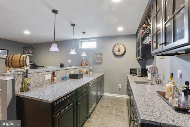 kitchen with light tile patterned floors, light stone counters, decorative light fixtures, dark brown cabinetry, and sink