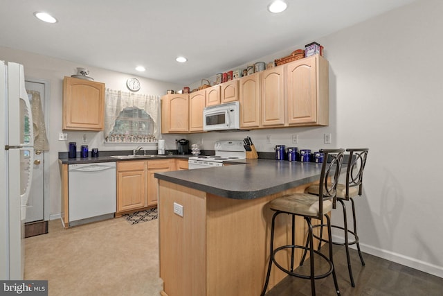 kitchen featuring sink, light brown cabinets, white appliances, and kitchen peninsula