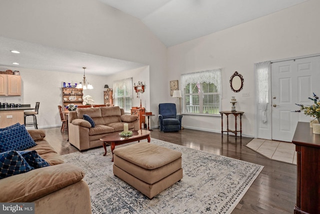 living room featuring lofted ceiling, dark hardwood / wood-style floors, and an inviting chandelier