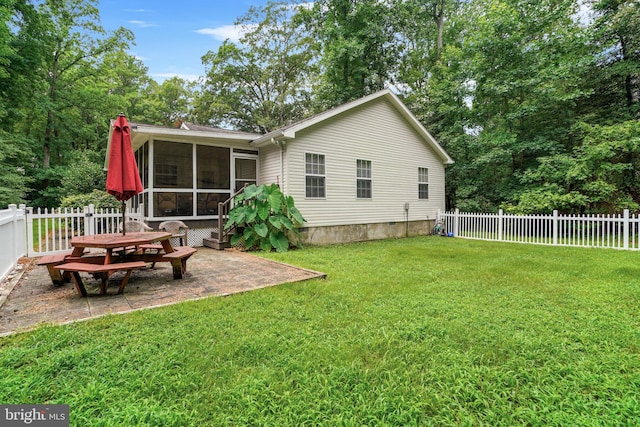 rear view of property with a sunroom, a lawn, and a patio area