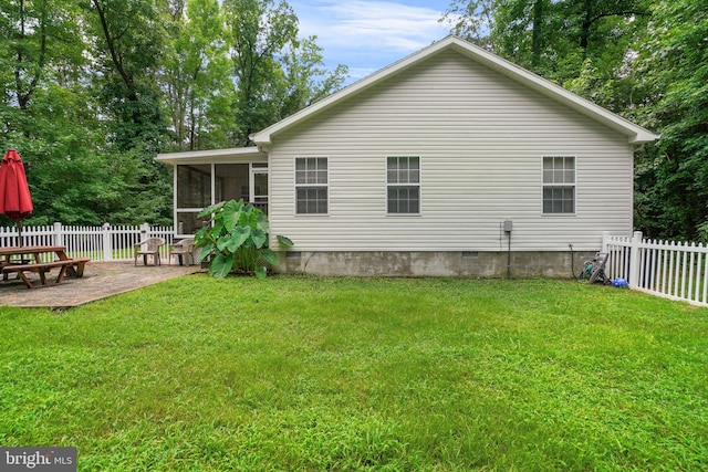 rear view of house featuring a lawn, a sunroom, and a patio area