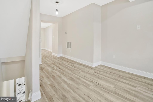 empty room with light wood-style floors, visible vents, and baseboards