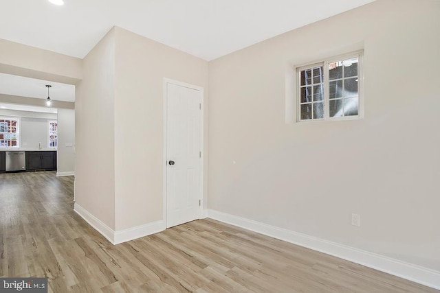 spare room with light wood-type flooring, a sink, and baseboards