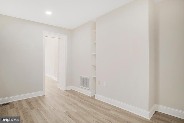 unfurnished room featuring baseboards, visible vents, and wood finished floors