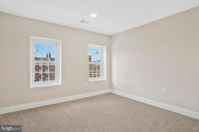 carpeted empty room with baseboards, visible vents, and recessed lighting