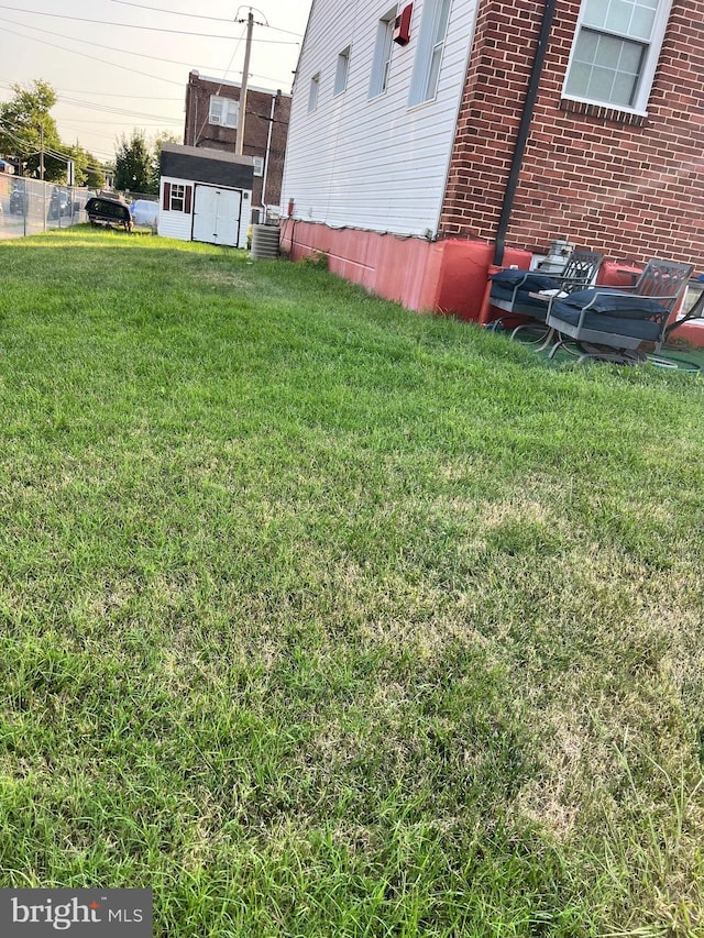 view of yard with central air condition unit and a storage unit