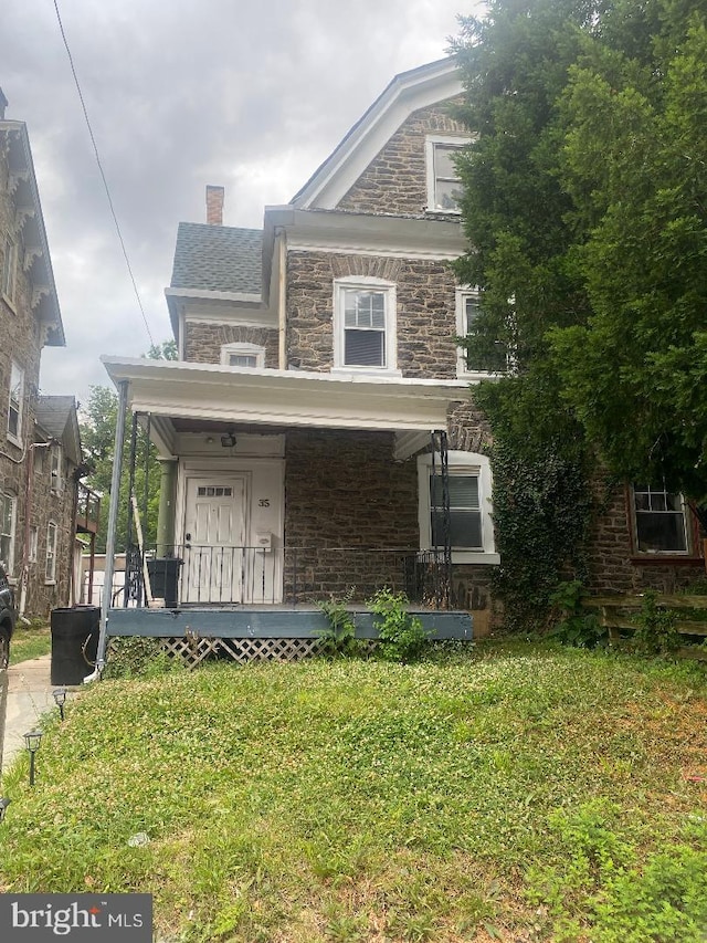 view of front of home featuring covered porch and a front lawn