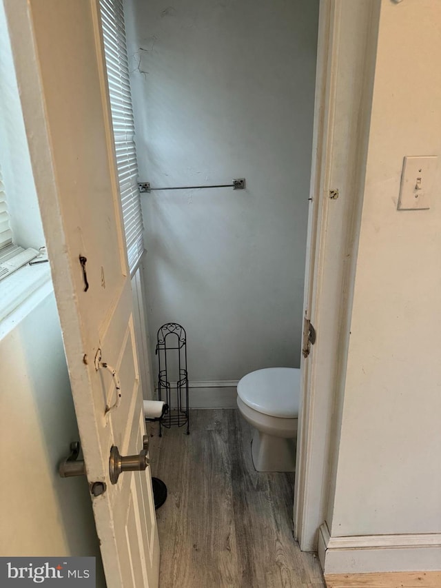 bathroom with a wealth of natural light, toilet, and hardwood / wood-style floors