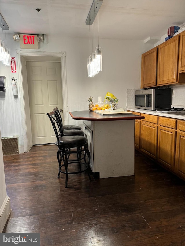 kitchen featuring a breakfast bar, decorative light fixtures, a center island, and dark hardwood / wood-style floors