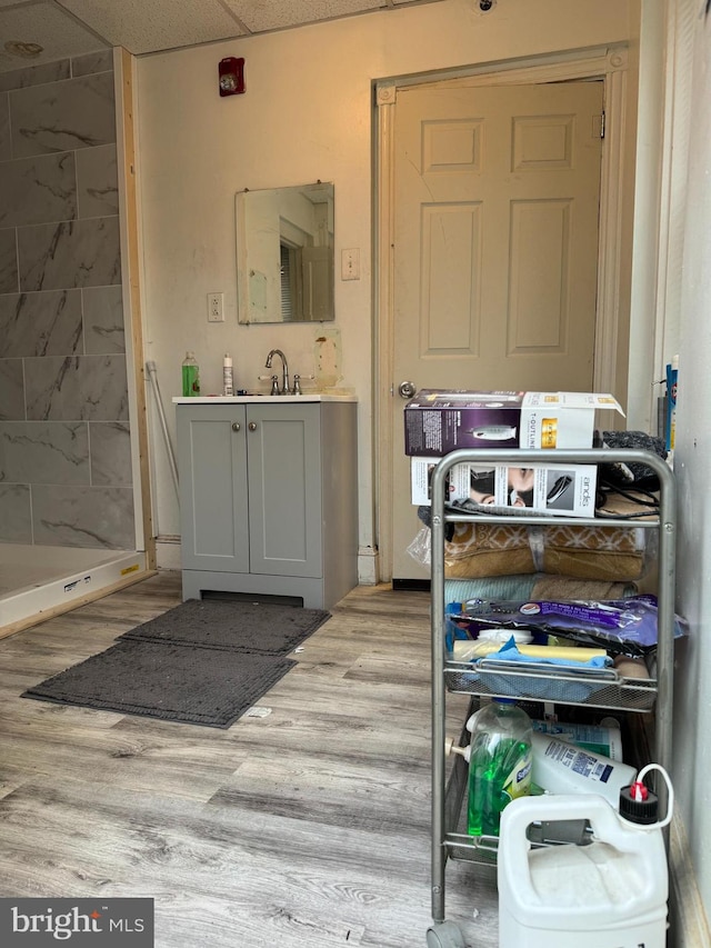 interior space featuring a shower, sink, hardwood / wood-style flooring, and a drop ceiling