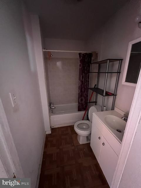 full bathroom featuring vanity, parquet flooring, shower / tub combo with curtain, and toilet