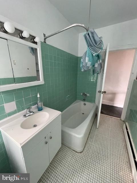 bathroom with tiled shower / bath, tile walls, vanity, tile patterned flooring, and backsplash