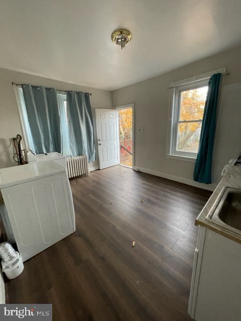 interior space with dark wood-type flooring, radiator, and sink