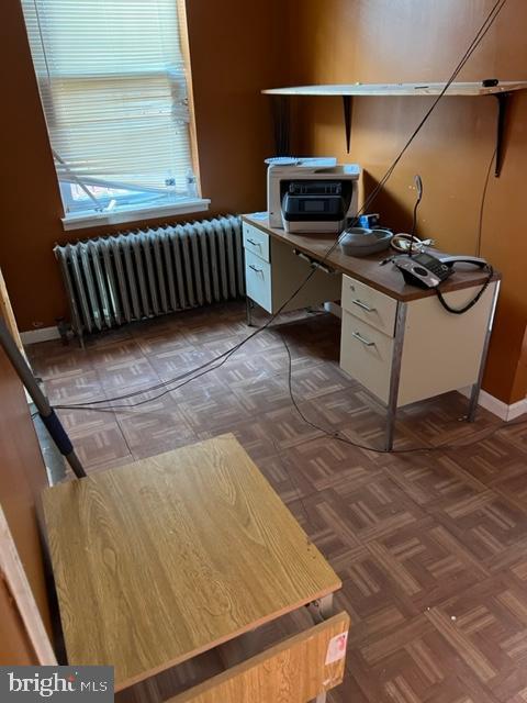 office featuring dark parquet flooring and radiator heating unit