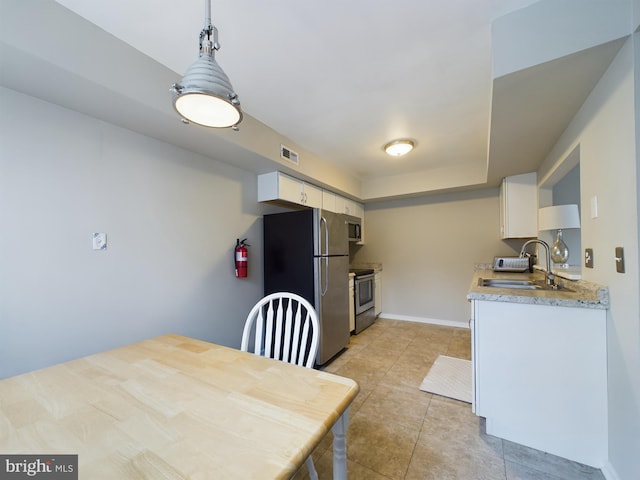 kitchen featuring appliances with stainless steel finishes, sink, pendant lighting, and white cabinets