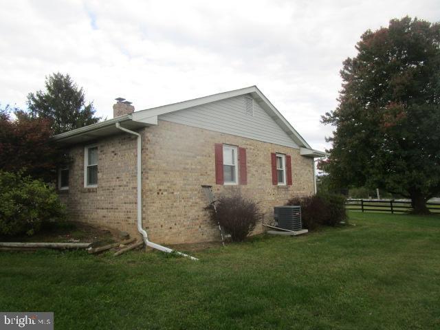 view of side of home featuring central AC unit and a yard