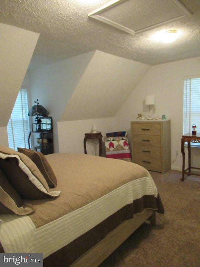 carpeted bedroom featuring a textured ceiling, vaulted ceiling, and multiple windows