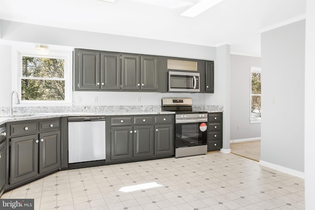 kitchen with ornamental molding, stainless steel appliances, gray cabinets, and sink