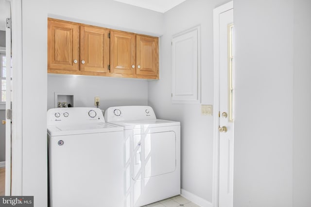 clothes washing area featuring cabinets and separate washer and dryer