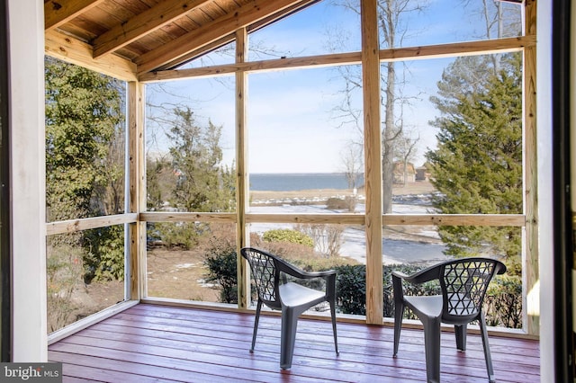 unfurnished sunroom featuring a water view, vaulted ceiling with beams, and wooden ceiling