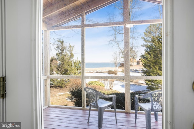 interior space featuring floor to ceiling windows, a water view, vaulted ceiling with beams, and wood-type flooring
