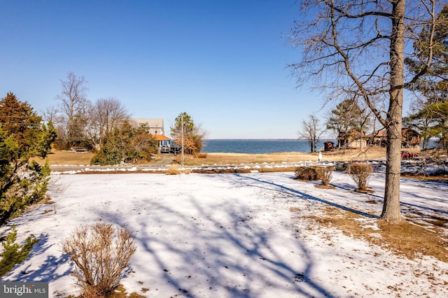 yard covered in snow featuring a water view