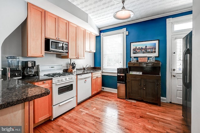 kitchen with lofted ceiling, sink, dark stone counters, light hardwood / wood-style floors, and stainless steel appliances