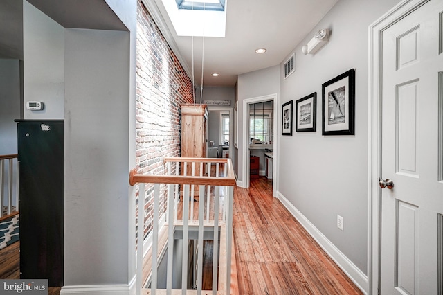 hall featuring wood-type flooring and a skylight