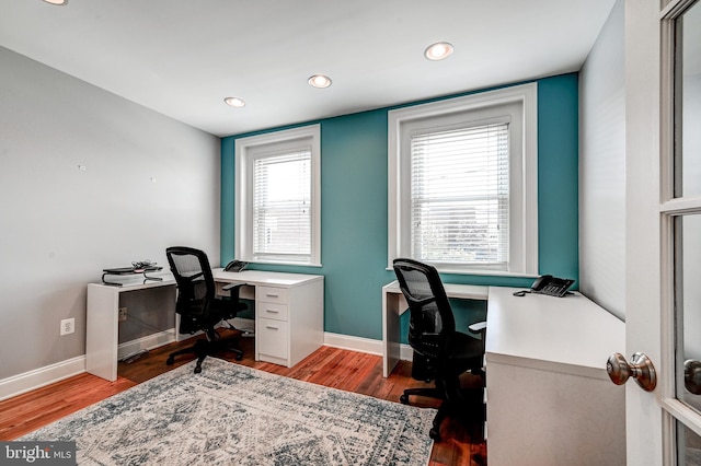 office with hardwood / wood-style flooring and a healthy amount of sunlight