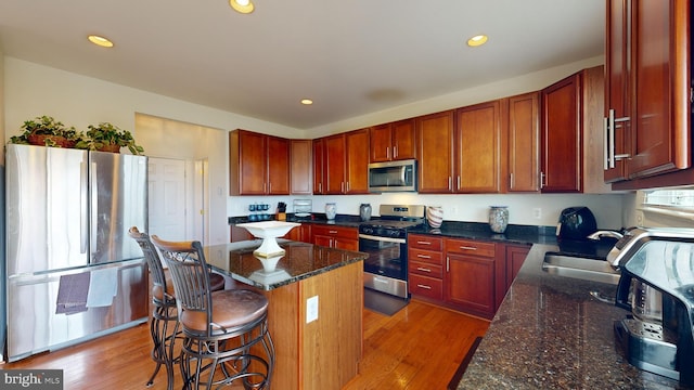 kitchen with stainless steel appliances, sink, a center island, and dark stone countertops