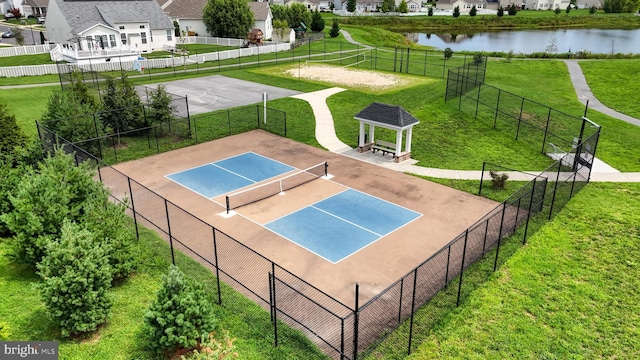 view of tennis court featuring a gazebo, a water view, and a yard