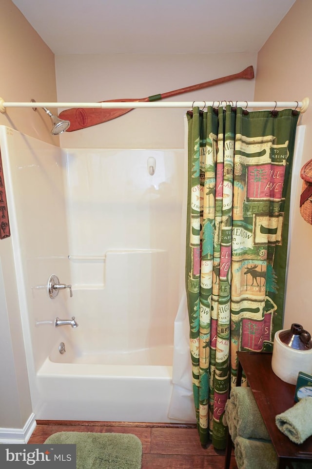 bathroom with hardwood / wood-style flooring and shower / bath combination with curtain