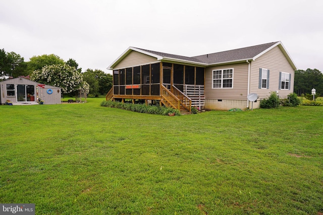 back of house with an outbuilding, a sunroom, and a lawn