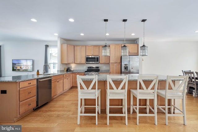 kitchen featuring a breakfast bar, light stone countertops, stainless steel appliances, and a center island