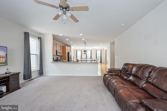 living area featuring baseboards, ceiling fan, recessed lighting, and light colored carpet