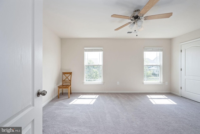 empty room featuring light carpet, visible vents, baseboards, and a wealth of natural light