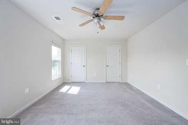 unfurnished bedroom with light carpet, ceiling fan, visible vents, and baseboards