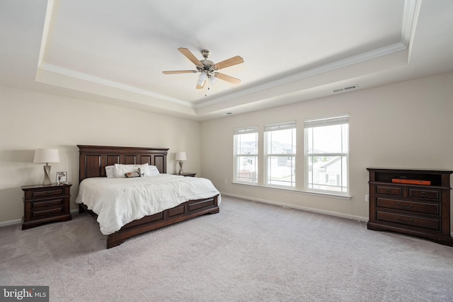 bedroom featuring a raised ceiling, light colored carpet, visible vents, and baseboards