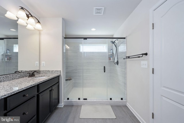 bathroom with a stall shower, vanity, visible vents, and baseboards