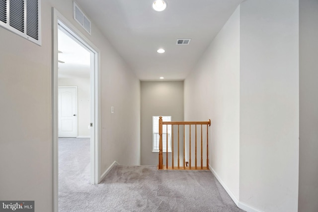 corridor featuring light carpet, visible vents, and recessed lighting