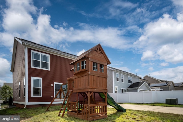 view of playground with a yard, fence, and central AC unit