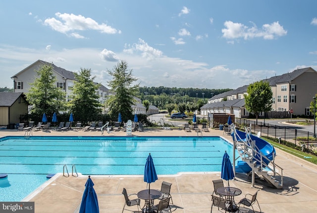 view of swimming pool with a patio, fence, and a residential view