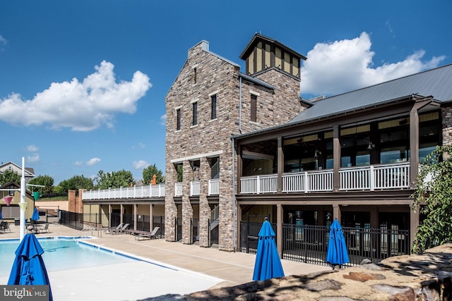 exterior space featuring stone siding, a patio, fence, and a community pool