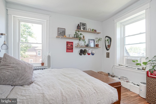 bedroom with multiple windows, cooling unit, and light hardwood / wood-style floors