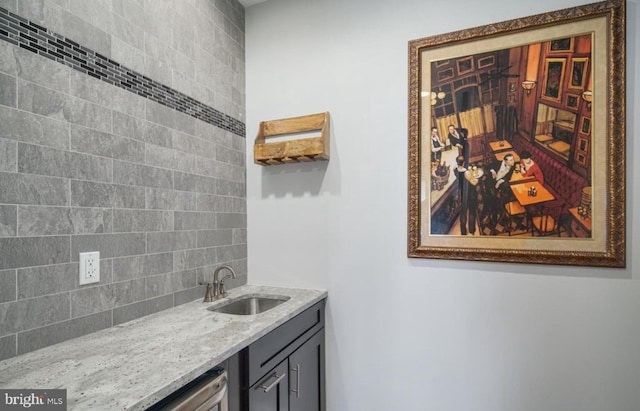 bar with light stone counters, sink, and tasteful backsplash