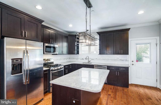 kitchen with appliances with stainless steel finishes, a kitchen island, dark brown cabinets, decorative light fixtures, and sink